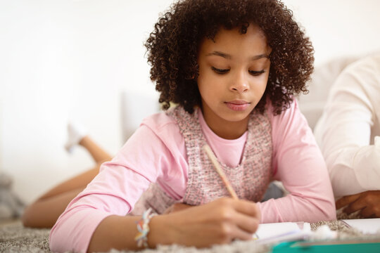 African American Preadolescent Girl Focused On Drawing Lying At Home