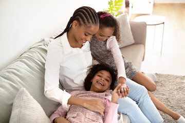 African American Mommy And Daughters Playfully Tickling Each Other Indoor