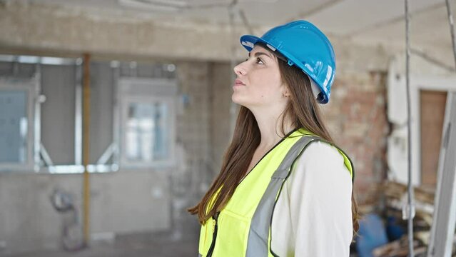 Young beautiful hispanic woman builder breathing at construction site