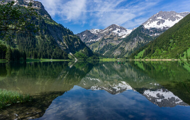 Wandern in Österreich, nahe dem Allgäu: der schöne Bergsee Vilsalpsee in den Tannheimer Bergen in Tirol mit Angler und Boot später Frühling, früher Sommer im Mai