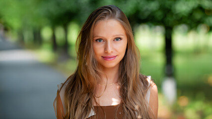 portrait of young smiling attractive caucasian woman in jeans jacket in the park at summer