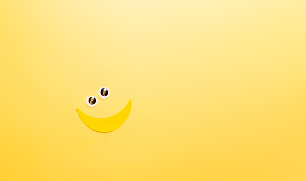 Banner con emoticones de carita sonriente y banana con ojitos. espacio para texto, en fondo amarillo, concepto de dia mas feliz del año, happy yellow day, verano.