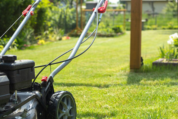 Lawn mower cutting grass in the garden. Gardening.