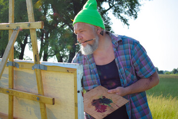 Midsection trendy enthusiastic painter working outdoors having creative inspiration painting...