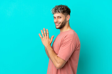 Young handsome caucasian man isolated on blue background scheming something