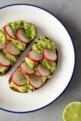 Homemade Radish Avocado Toast with Salt and Pepper on a Plate, top view. Close-up.