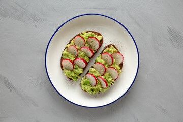 Homemade Radish Avocado Toast with Salt and Pepper on a Plate, top view. Close-up.