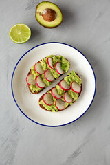 Homemade Radish Avocado Toast with Salt and Pepper on a Plate, top view. Close-up.