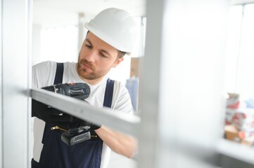 Construction worker installing metal profile for interior partition wall, while building a new...