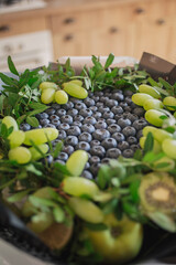 a fruit bouquet of blueberries and grapes stands on a table in the kitchen