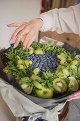a fruit bouquet of blueberries and grapes stands on a table in the kitchen
