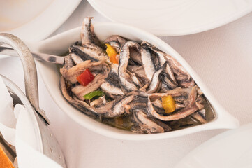 Bowl with marinated anchovies in oil and pieces of peppers