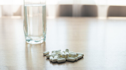 Pills, medicines and a glass of water on a wooden table