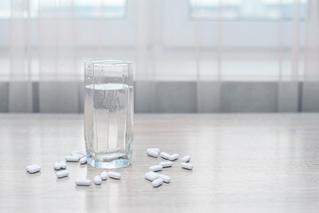 Pills, medicines and a glass of water on a wooden table