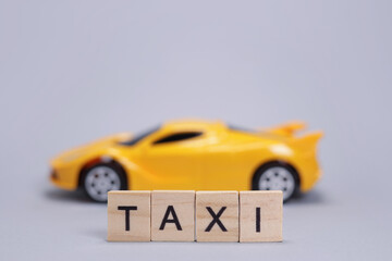 Toy car and the taxi made of wooden letters, cab passenger transportation concept