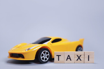 Toy car and the taxi made of wooden letters, cab passenger transportation concept