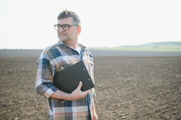 A farmer works in a field sown in spring. An agronomist walks the earth, assessing a plowed field...