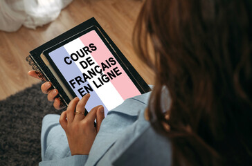 A woman holds a tablet in her hands on the screen of which it is written - Online learning French