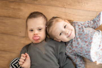 Boy plays with his younger sister on the bed in home bedroom. Down syndrome and ASD