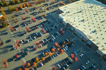 View from above of american grocery store with many parked cars on parking lot with lines and...