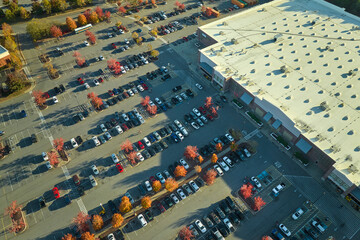 View from above of american grocery store with many parked cars on parking lot with lines and markings for parking places and directions. Place for vehicles in front of a strip mall center © bilanol