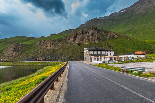 Road and abandoned house in the mountains under stormy sky in Italy.