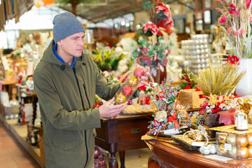 Man shopping in home goods store and buying christmas decorations.
