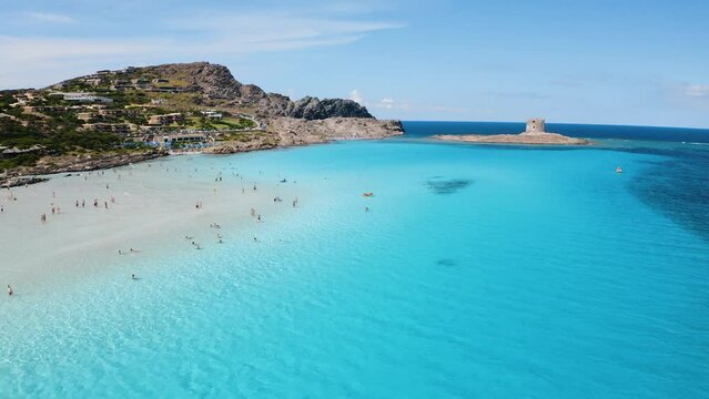 Aerial view of famous La Pelosa beach at sunny summer day. Stintino, Sardinia island, Italy. Top view of white sandy beach, umbrella, swimming people, clear blue sea, old tower. Tropical seascape