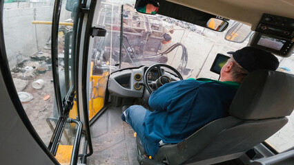 Man driving forward and backward a front loader while pushing, scooping, and dumping trash at a waste transfer station, inside the cabin view.