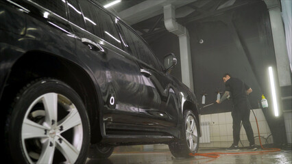 Man worker washing car's alloy wheels on a car wash. Luxury car wash