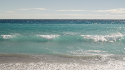 blue waves with strong wind on a sandy empty beach in Cannes in spring