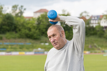 Sports in oldAn elderly man goes in for sports on the background of the stadium on a summer eveningage