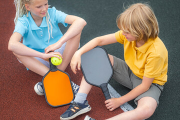  pickleball game, relaxing pickleball players kids boy and girl with yellow ball and paddles...