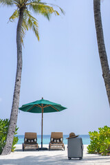 A suitcase and a straw hat against the backdrop of the landscape of the Maldives. Travel and tropical vacation concept