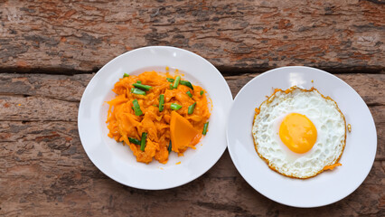 close up traditional thai food stir fried pumpkin with egg in white plate on old wood background - generative ai