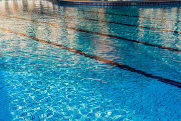 Beautiful luxury umbrella and chair around outdoor swimming pool in hotel and resort with coconut tree against blue sky. Beach in the background. Reflections in the water