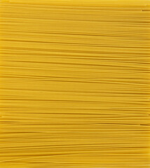 Thin, yellow, raw spaghetti is laid out as a background on the table. Italian food. Paste. - obrazy, fototapety, plakaty
