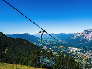 Chairlift ski lift chair going upwards no people empty in Austria, Carinthia, during summer with mountains in the background, clear sky, copy space