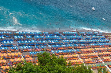 From the top of Positano, panoramic photograph of the beach on a summer day with the beach umbrellas symmetrically placed and in the same colors. Amalfi Coast, Italy