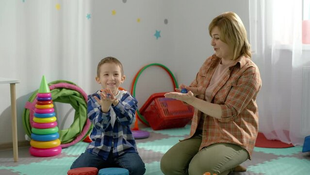 The teacher works individually with the child on the development of hand motility. Happy boy in classroom at school. Active lessons for children. High quality 4k footage