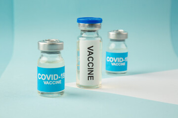 Front close view of COVID- vaccine ampoules on pastel blue and white background with free space