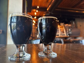 Dark beer with froth in a glass stands on the table at a cafe, restaurant. Top view. Creative ideas of drinks and food. Alcoholic drink production. 