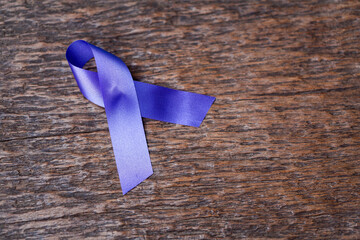 Purple ribbon for the awareness about the unacceptability of the violence against women on dark...