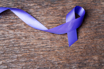 Purple ribbon for the awareness about the unacceptability of the violence against women on dark...