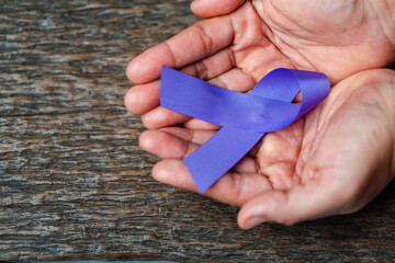 Purple ribbon for the awareness about the unacceptability of the violence against women on dark...