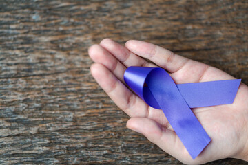 Purple ribbon for the awareness about the unacceptability of the violence against women on dark...