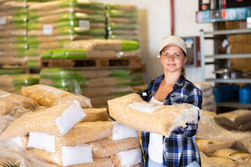 Positive woman worker loading sacks at warehouse store