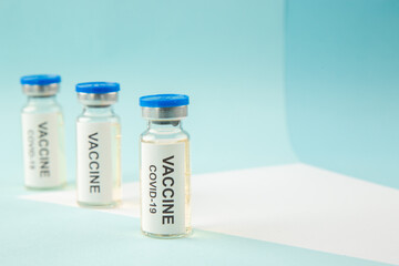 Front view of COVID- VACCINE in closed ampoules on the right side on blue wave background with free space