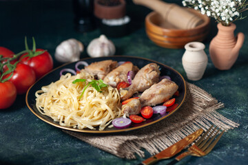Front view of tasty pasta meal with chickens and vegetables on a plate flowers on nude towel wooden hammer