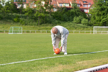 Obraz premium An elderly man goes in for sports on the background of the stadium on a summer evening 